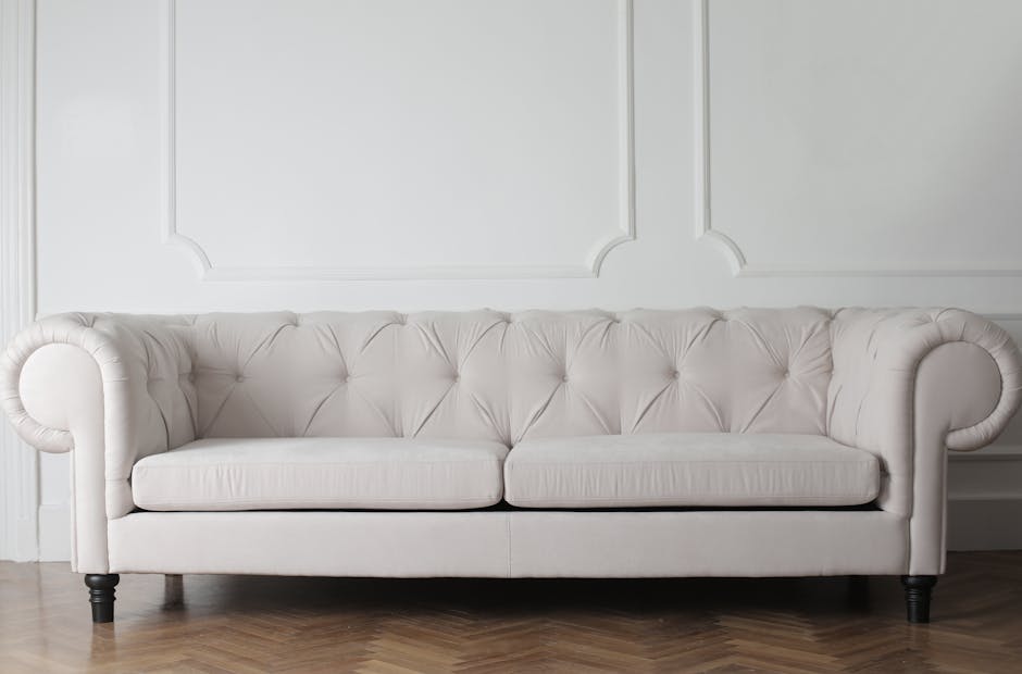 The image depicts a luxurious antique living room corner illuminated by soft, warm lighting. A dark, ornately patterned velvet sofa with carved wooden detailing is positioned in front of decorative wa
